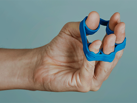 closeup of a man's hand using an elastic band to exercise his fingers